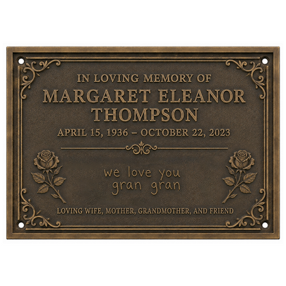 A rectangular bronze-toned memorial plaque with engraved text reading 'In Loving Memory of Margaret Eleanor Thompson' and 'we love you gran gran,' plus decorative floral corner details and rose motifs, shown on a plain white background.