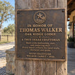 Antique bronze appreciation plaque with raised lettering installed on a weathered wooden post
